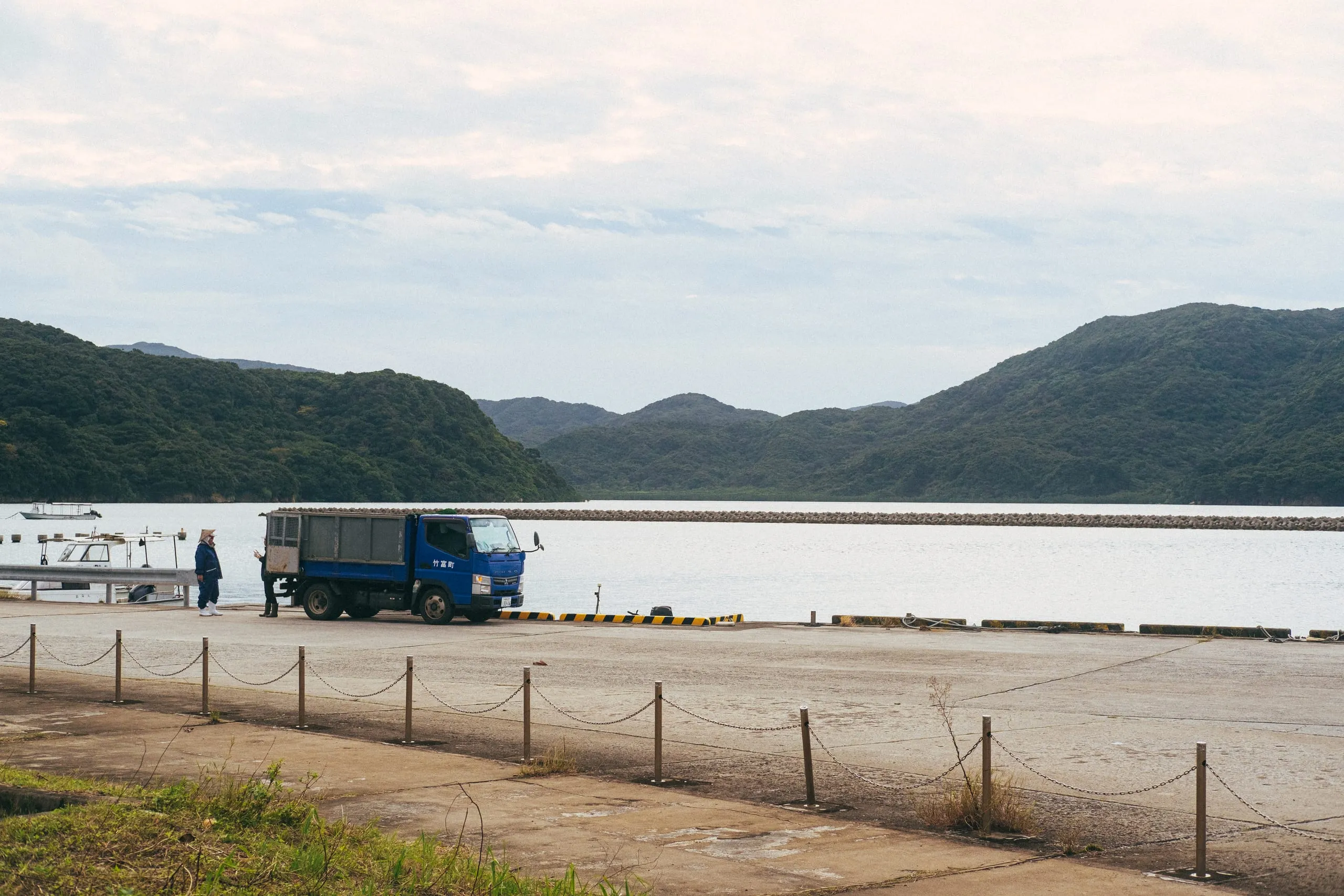 Two fishermen converse beside their truck in Shirahama harbour quay